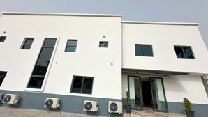 A modern building with multiple windows, air conditioning units, and a flat roof. - Bayford Suites (Abuja)