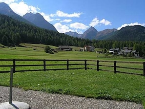 A rural landscape with a fenced field, a building, and mountains in the background.