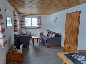 A furnished living room with a sofa, a small table, and a television.