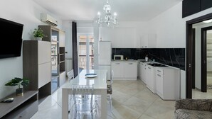 Een moderne keuken met witte kasten, een eettafel en een kroonluchter.