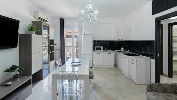 A modern kitchen with white cabinets, a dining table, and a chandelier. - Apartment 'Mirosa' with Balcony, Wi-Fi and Air Conditioning (Pompei)