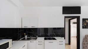 A modern kitchen with white cabinetry, a black marble backsplash, and a built-in microwave. - Apartment 'Mirosa' with Balcony, Wi-Fi and Air Conditioning (Pompei)