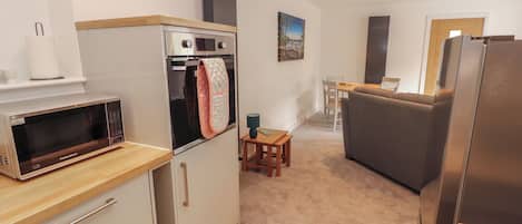 A compact kitchen with a microwave, oven, and refrigerator.