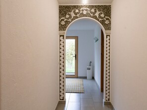 A hallway with a decorative archway leading to a room with a door and a small sink. - Schaivel, (Müstair) by Interhome (Müstair)