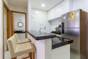 Eine kompakte Küche mit einem eingebauten Kühlschrank, einer Spüle und einem Barhocker.