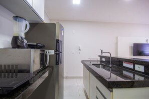 A kitchen with a blender, microwave, refrigerator, sink, and a flat-screen TV mounted on the wall. - Apto c Garagem 400m da Praia dos Sete Coqueiros (Maceió)