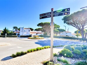 Ein Wegweiser mit mehreren Pfeilen, die in Richtung 'Academia de Tênis', 'Centro Center' und 'Vale do Golfe' zeigen.
