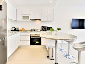 A modern kitchen with white cabinetry, a built-in microwave, a coffee maker, and a sink. - Apartment  by Interhome (Vilamoura)