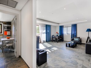 A modern living room with a dining area, a kitchen with an oven and microwave, and a large window with curtains. - Apartment  by Interhome (Albufeira)