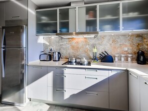 A modern kitchen with stainless steel appliances, a marble backsplash, and a built-in oven. - Falesia Beach A by Interhome (Albufeira)