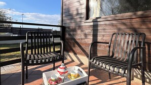 Een terras met twee zwarte metalen stoelen en een tafel met een dienblad thee en kopjes.