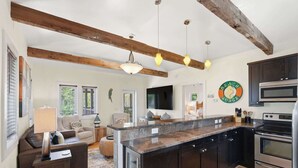A modern kitchen with dark cabinetry, a granite countertop, and stainless steel appliances. - Yew 2!- House + Carriage House- Steps to Beach! (Santa Rosa Beach)