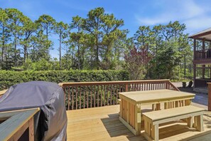 A wooden deck with a table and benches, surrounded by trees and a fence. - Double Yew | Forest Cottage, Dog-Friendly (Santa Rosa Beach)