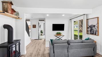 Un salon moderne avec une cheminée, un canapé, un téléviseur et une grande fenêtre.