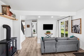 A modern living room with a fireplace, a sofa, a TV, and a large window.