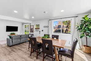 A modern living room with a sofa, dining table, chairs, and a TV.