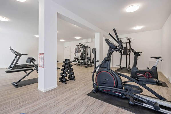 A gym with cardio machines, free weights, and a wall-mounted rack. - Vacation apartment with sauna, lake view and balcony on the Szczecin Lagoon (Zirchow)