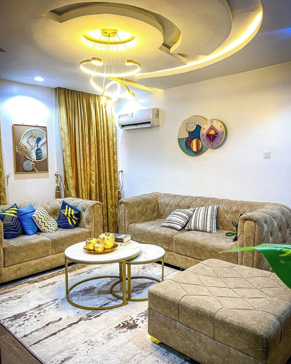 A living room with a sectional sofa, a round coffee table, and a modern chandelier.