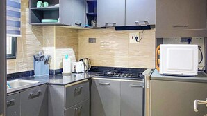 A modern kitchen with grey cabinets, a microwave, a kettle, and a toaster. - Jay's Wood Hotel And Apartment (Benin City)