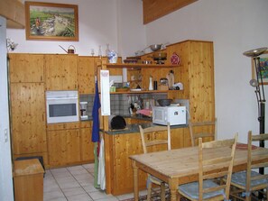Eine Küche mit Holzausstattung, einer Mikrowelle, einem Herd und einem Esstisch mit Stühlen.