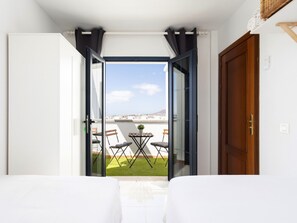 A room with a view of a cityscape through an open door, a small table with chairs, and a wooden door. - TEBAR BEACH by Interhome (Playa Blanca)