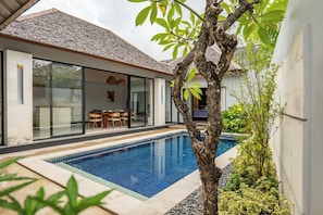 Ein modernes Haus mit Schwimmbad, Essbereich und einer großen Glasdoor, die zu einem Raum führt.