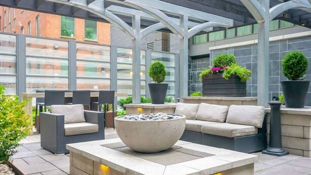 Een terras buiten met zitplaatsen, een vuurkorf en plantenbakken.