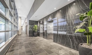 A modern hallway with glass walls, marble walls, and potted plants. - FIFA Watchpad Oasis; Minutes to the Stadium (Toronto)