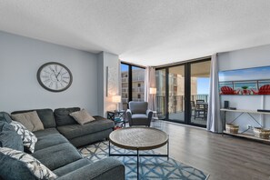 Un salon moderne avec un canapé, une table basse, une horloge et une vue sur le balcon.