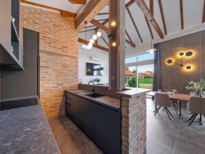 Una cocina moderna con ladrillo visto, una isla integrada y una zona de comedor con mesa y sillas.