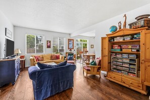 Ein Wohnzimmer mit blauem Sofa, Holzschrank mit Gesellschaftsspielen und Fernseher.