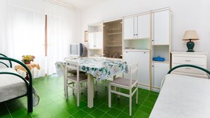 Une pièce comprenant une table à manger, des chaises, un lit, un téléviseur, une armoire et une lampe.