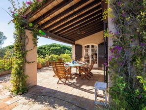 An outdoor patio with a table and chairs, surrounded by stone walls and vegetation. - Les Boissines by Interhome (Sainte Maxime)
