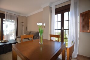 Ein Essbereich mit einem Holztisch, Stühlen, einer Blumenvase und Blick durch ein Fenster.