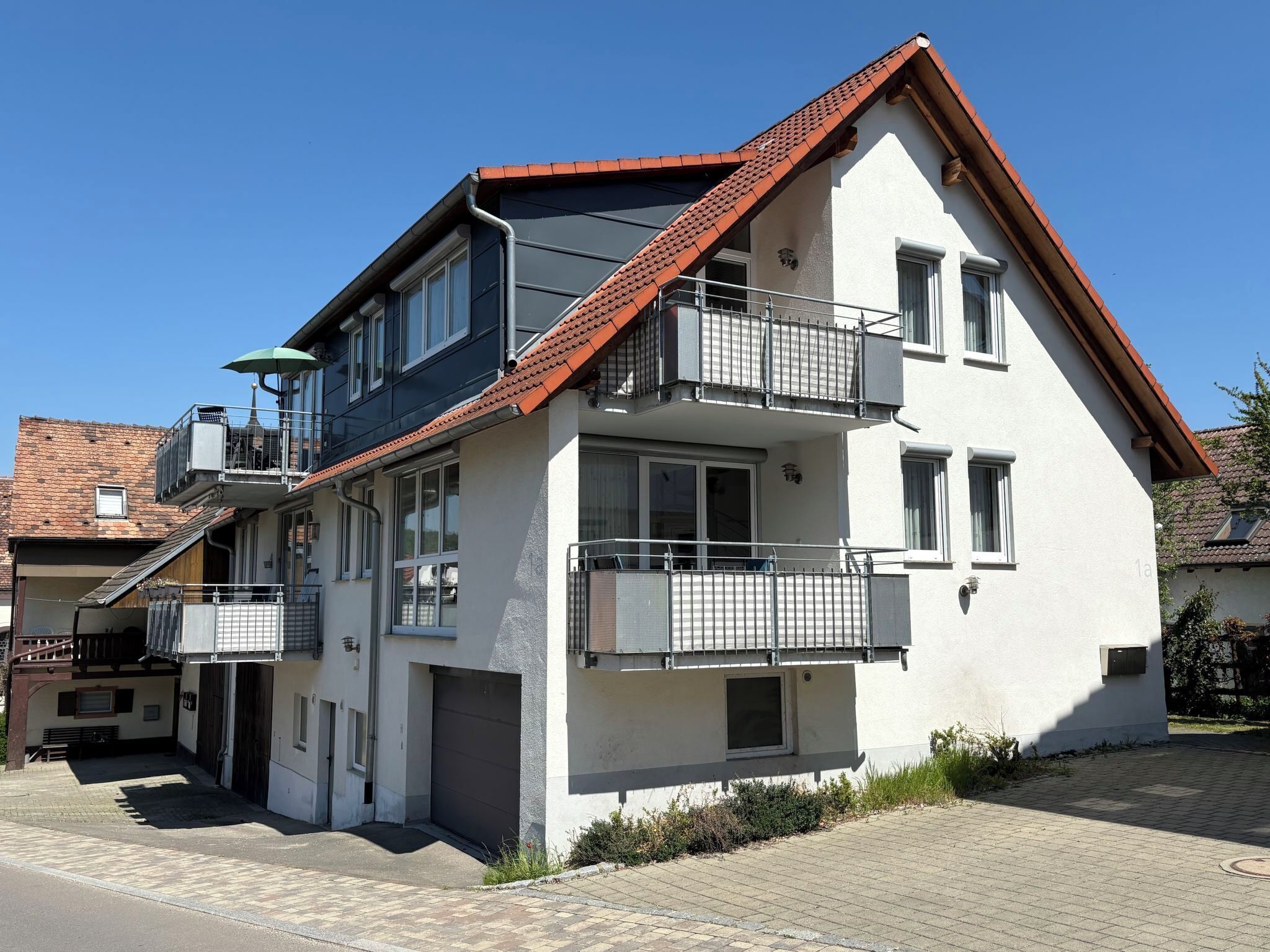Un immeuble résidentiel de deux étages, doté d’un toit recouvert de tuiles rouges, de balcons et d’un garage.