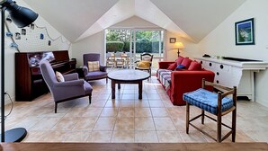 A spacious loft with a high ceiling, a dining area, and a view through large windows.