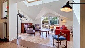 A spacious loft with a high ceiling, a piano, a red sofa, and a dining area.