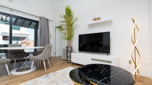 A modern living room with a dining area, a large TV, and a decorative plant. - Kaya Canhas by LovelyStay (Poiso)