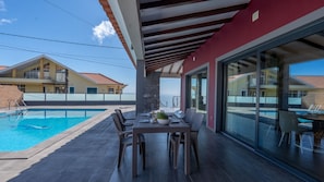 A rooftop pool area with a dining table and chairs, a stone pillar, and a view of neighboring buildings. - Kaya Canhas by LovelyStay (Poiso)