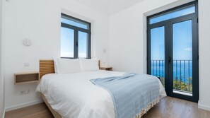 A bedroom with a bed, a window, a balcony, and a view of the sea. - Papaya Villa by LovelyStay (São Gonçalo)