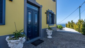 A building with a yellow facade, a dark blue door, and two potted plants. - Papaya Villa by LovelyStay (São Gonçalo)