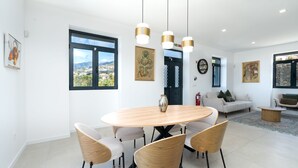 Un espace de salle à manger moderne avec une table ronde, quatre chaises et des luminaires suspendus.