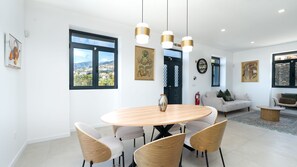 A modern dining area with a round table, four chairs, and pendant lights. - Papaya Villa by LovelyStay (São Gonçalo)
