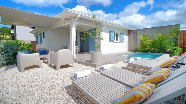 A covered outdoor area with lounge chairs, a pool, and a patio with seating. - SeaRock – Elegant Villa with Private Pool and Tropical Garden at Le Diamant (LE DIAMANT)