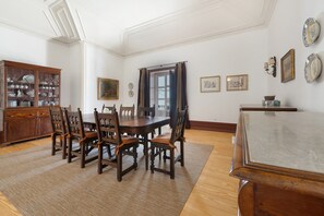 A dining room with a wooden table and chairs, a cabinet with glass doors, and framed artwork on the walls.