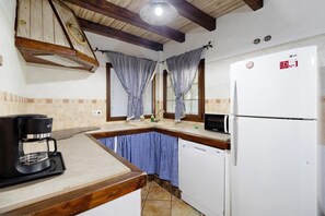 A compact kitchen with a coffee maker, a white refrigerator, and checkered curtains.