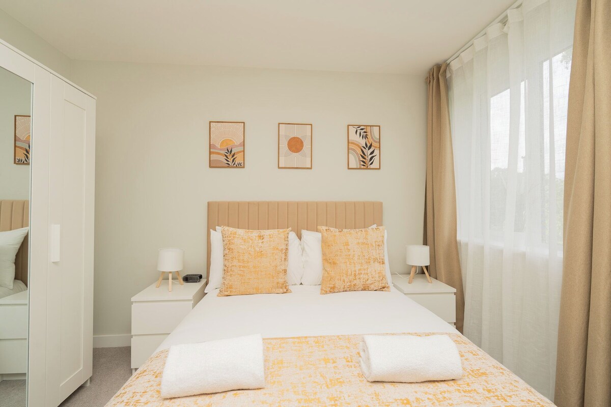 A hotel room with a bed, two bedside tables, a wardrobe, and three wall art pieces.