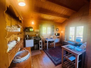 Acogedor interior de cabaña con cocina, comedor y zona de estar con vistas al exterior.
