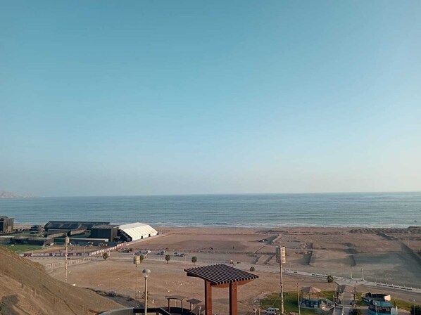 Une vue sur la plage, avec un pavillon, un grand bâtiment et un ciel dégagé.