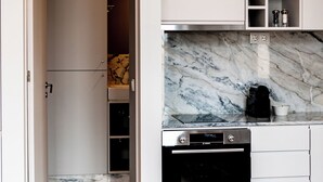A compact kitchen with a built-in oven, a marble backsplash, and a wooden floor. - 18th Century Italia Suite w/ Historic Charm & Modern Luxury in Central Porto 2N (Porto)
